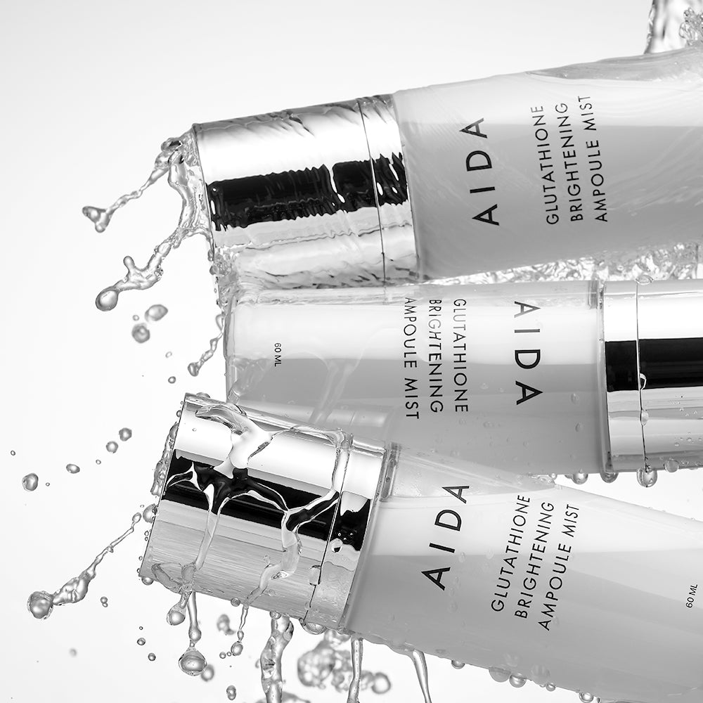 AIDA Glutathione Brightening Ampoule Mist bottles with water cascading over them, showcasing the luxurious and sleek design of the bottles while highlighting the refreshing and hydrating nature of the product.