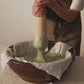 Video still showing hands vigorously mixing a fresh green cleanser in a traditional mortar, demonstrating the manual process of blending natural ingredients to create a smooth, artisanal skincare product