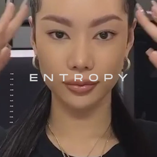 a young woman applying a perm lotion to her eyebrows using a detailed brush, part of a brow lift perm kit procedure to enhance and shape eyebrows effectively.