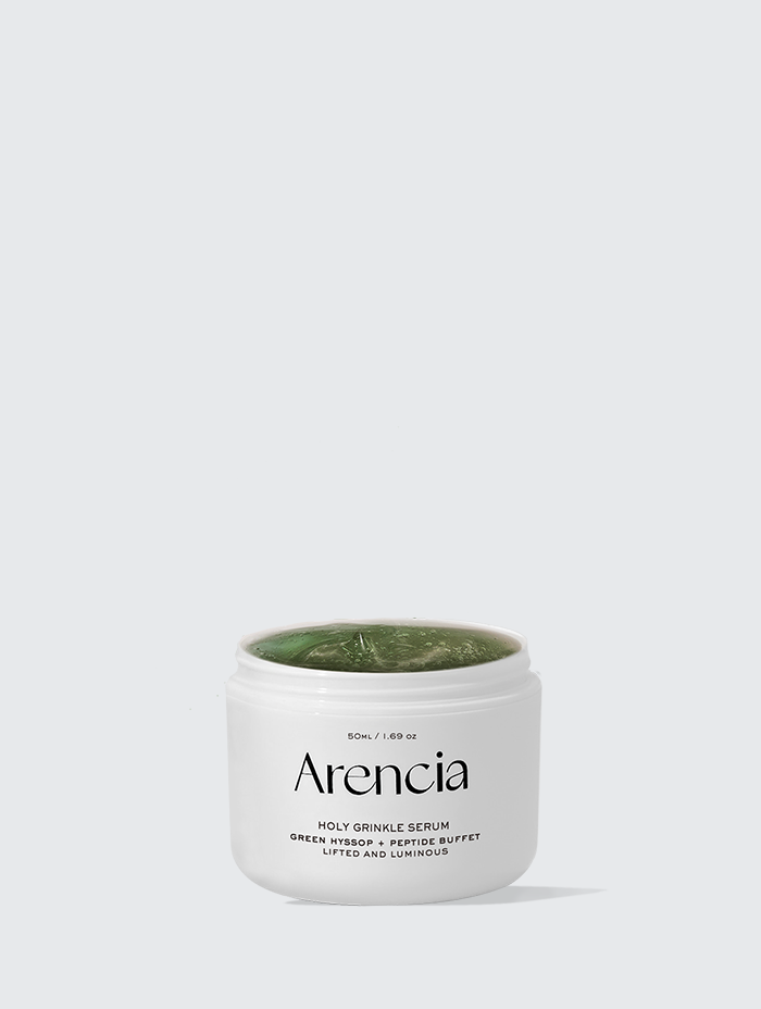 A jar of Arencia Holy Grinkle Serum with a green, gel-like texture, labeled "Holy Grinkle Serum - Green Hyssop + Peptide Buffet - Lifted and Luminous.